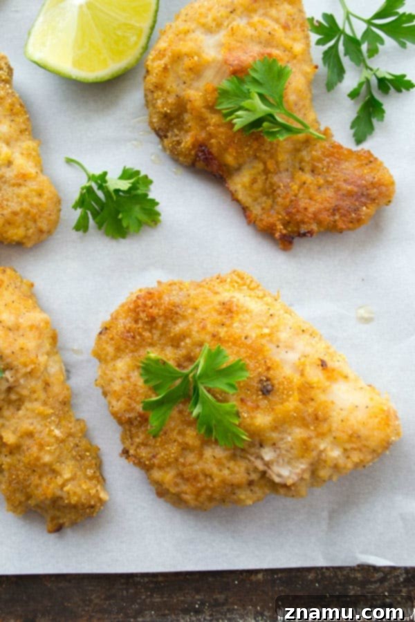 Golden Crispy Oven Chicken Tenders 7 Uncooked chicken tenders, fully coated in breading, laid out on a baking sheet before baking.