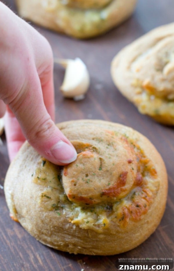 Irresistible Garlic Cheese Spirals 7 A freshly baked cheesy garlic spiral roll, pulled apart to reveal the soft, fluffy interior and the luscious melted cheese and garlic within.