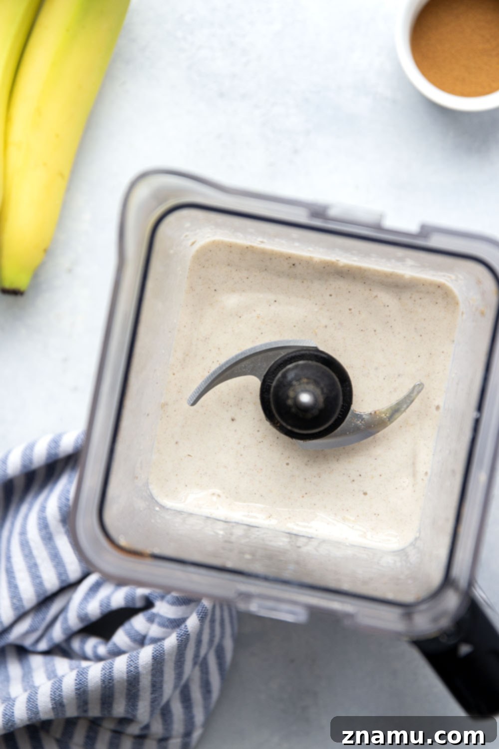 Spiced Banana Bliss Smoothie 4 An overhead shot of a glass of banana chai smoothie, with whole spices like star anise and cinnamon sticks scattered around the base, highlighting the natural ingredients.