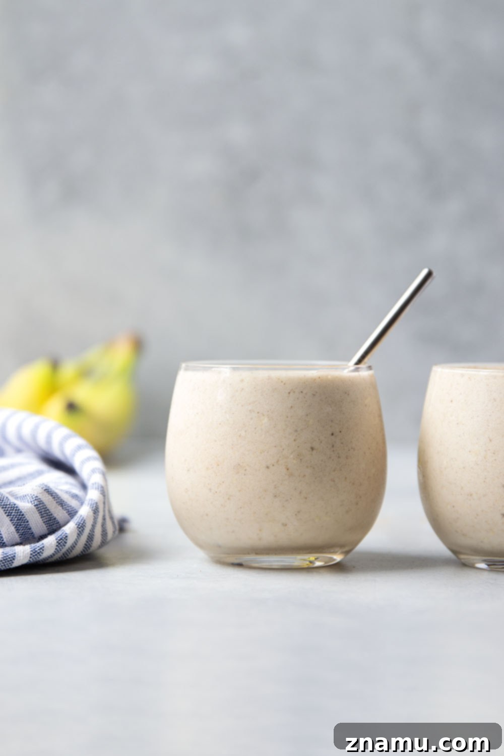 Spiced Banana Bliss Smoothie 5 A person pouring the freshly blended banana chai smoothie from a blender into a glass, showing the creamy texture.