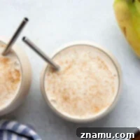 Spiced Banana Bliss Smoothie 8 Creamy banana chai smoothie in a glass, garnished with a sprinkle of cinnamon, next to a bowl of fresh spices.