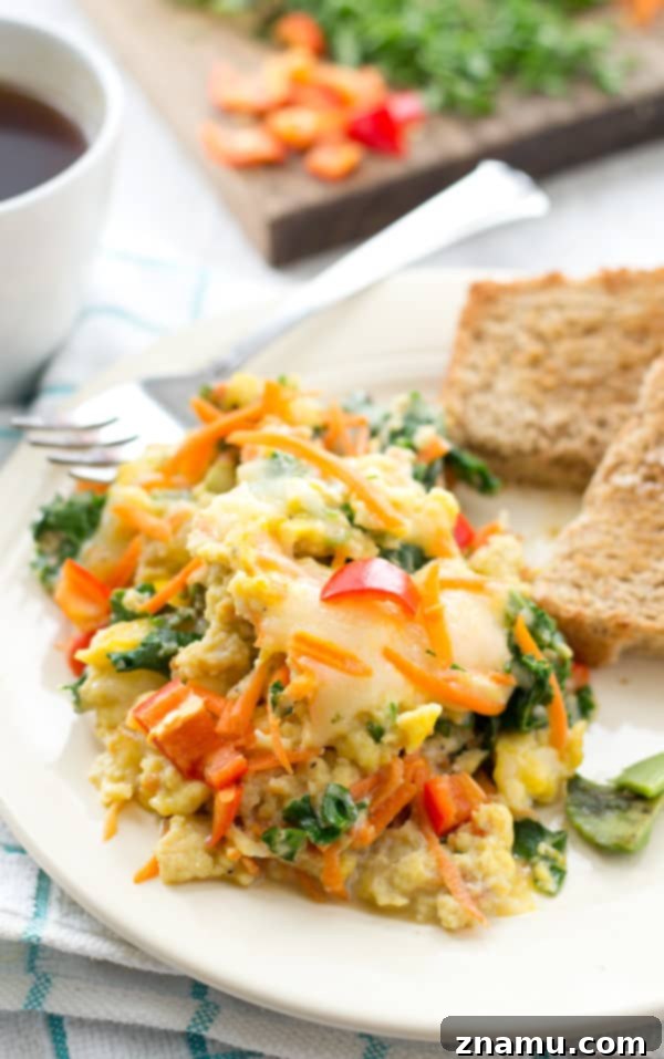 Close-up of fluffy scrambled eggs with colorful vegetables and cheese
