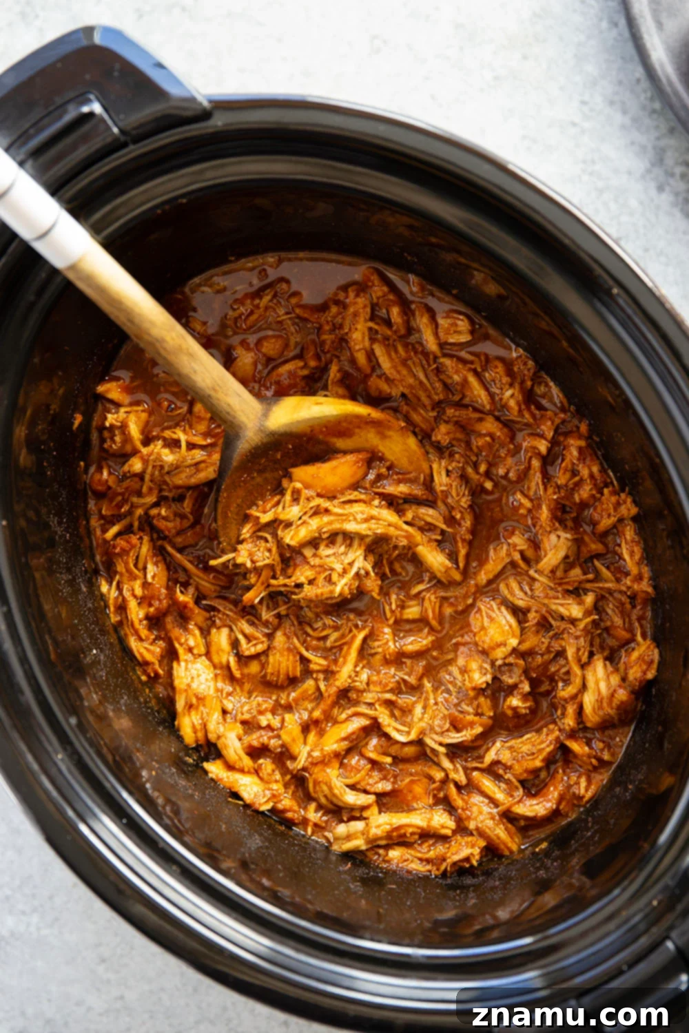 Effortless Slow Cooker BBQ Pulled Chicken 3 Close-up of slow cooker BBQ pulled chicken simmering in a rich sauce.