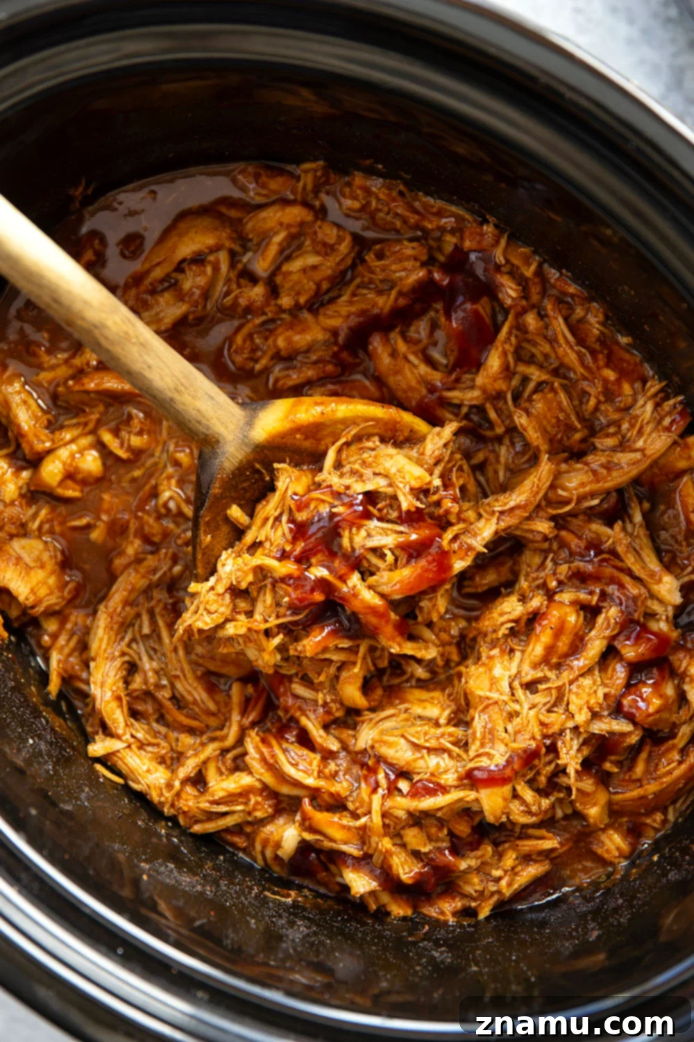 Effortless Slow Cooker BBQ Pulled Chicken 6 Serving of slow cooker BBQ pulled chicken with a side of coleslaw and a bun.