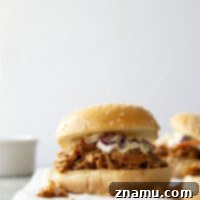 Slow cooker BBQ pulled chicken in a bowl with a side of coleslaw.