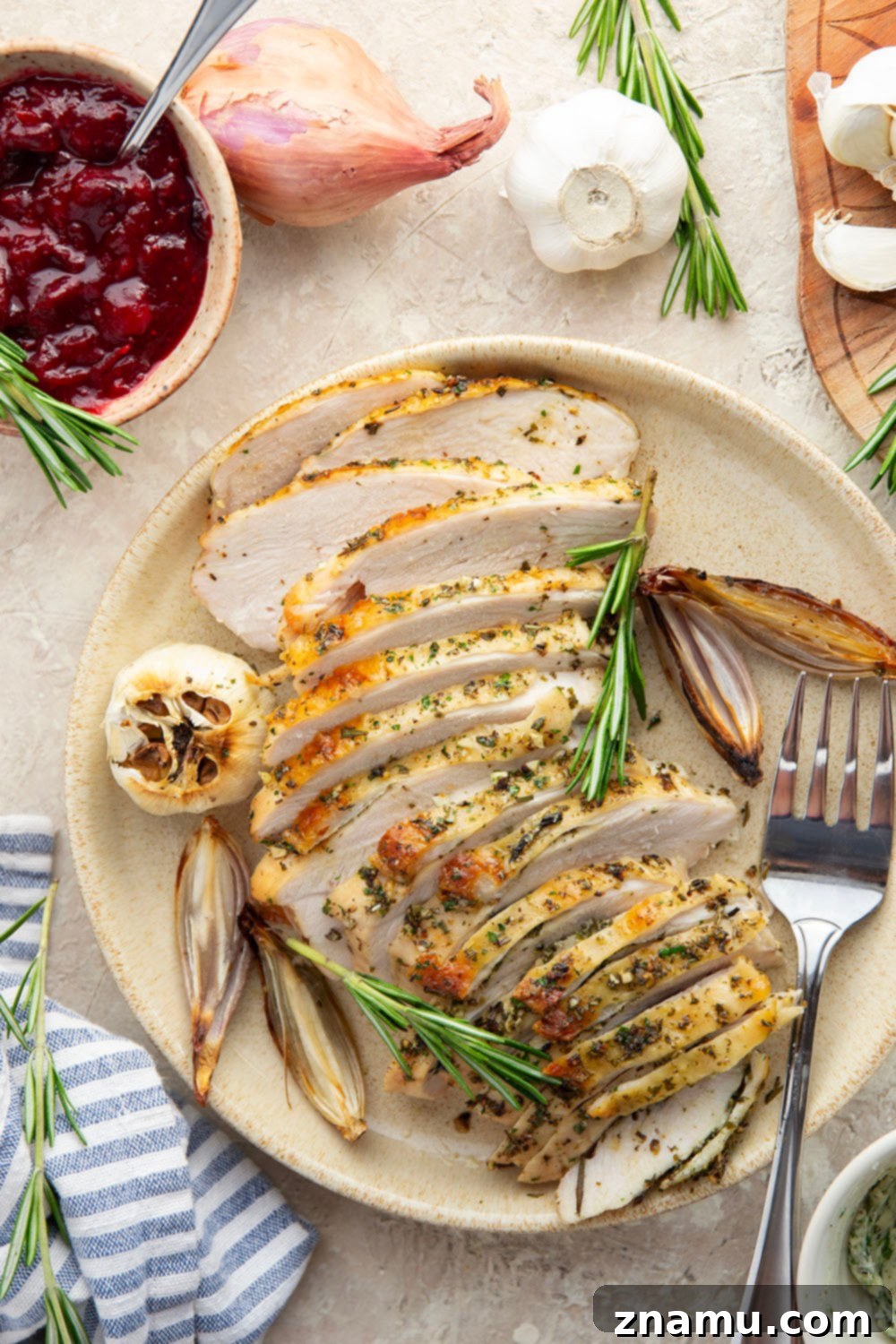 Uncooked turkey breast prepared with garlic herb butter and rosemary sprigs