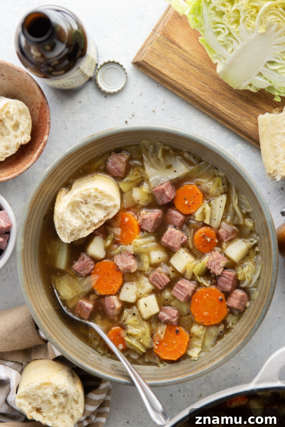 Hearty Corned Beef and Cabbage Stew 4 Assortment of fresh ingredients for corned beef cabbage soup, including diced corned beef, chopped green cabbage, sliced carrots, and cubed potatoes, neatly arranged on a wooden cutting board.