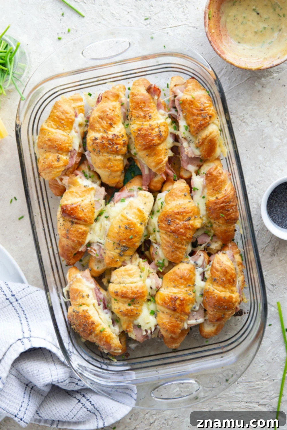 Melted Gruyere Ham Croissant Sliders 4 Hand holding a flaky Gruyere Ham and Cheese Croissant Slider, showcasing the melted cheese and a hint of sauce.