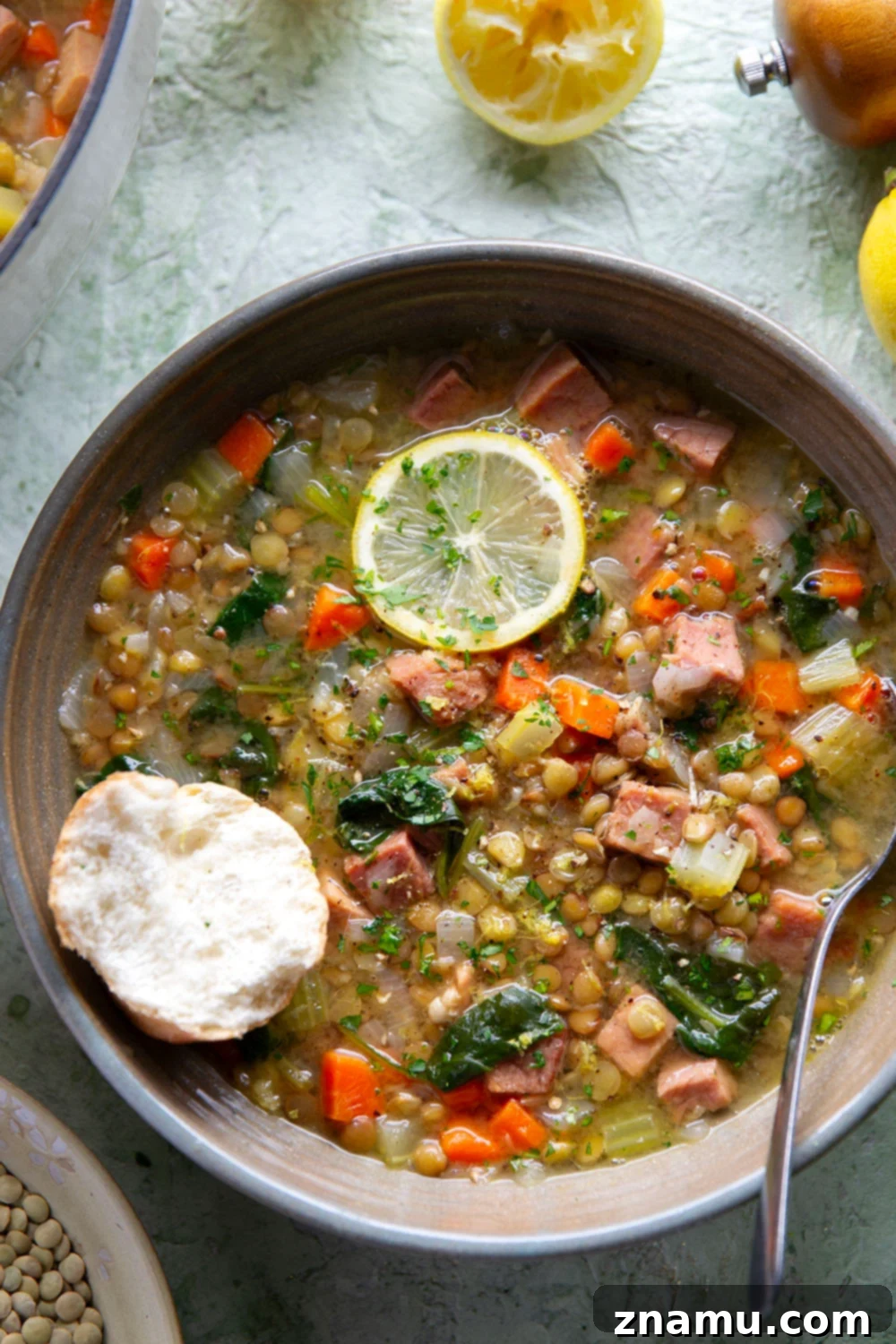 Hearty Lemon Lentil and Ham Soup 4 Close-up of fresh lemon slices and parsley being added to a bowl of Lemon Lentil Ham Soup.
