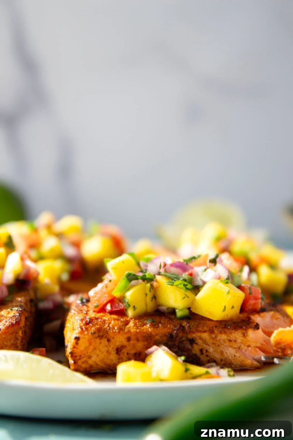 Marinated in a fresh lime and chili sauce, grilled to perfection, and topped with a super fresh mango salsa, this grilled chili lime salmon is an easy dinner that's full of flavor!