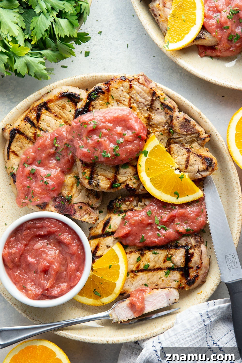 These grilled orange pork chops feature pork chops marinated in a fresh orange marinade, grilled until perfectly juicy, and served with a sweet and tangy rhubarb compote.