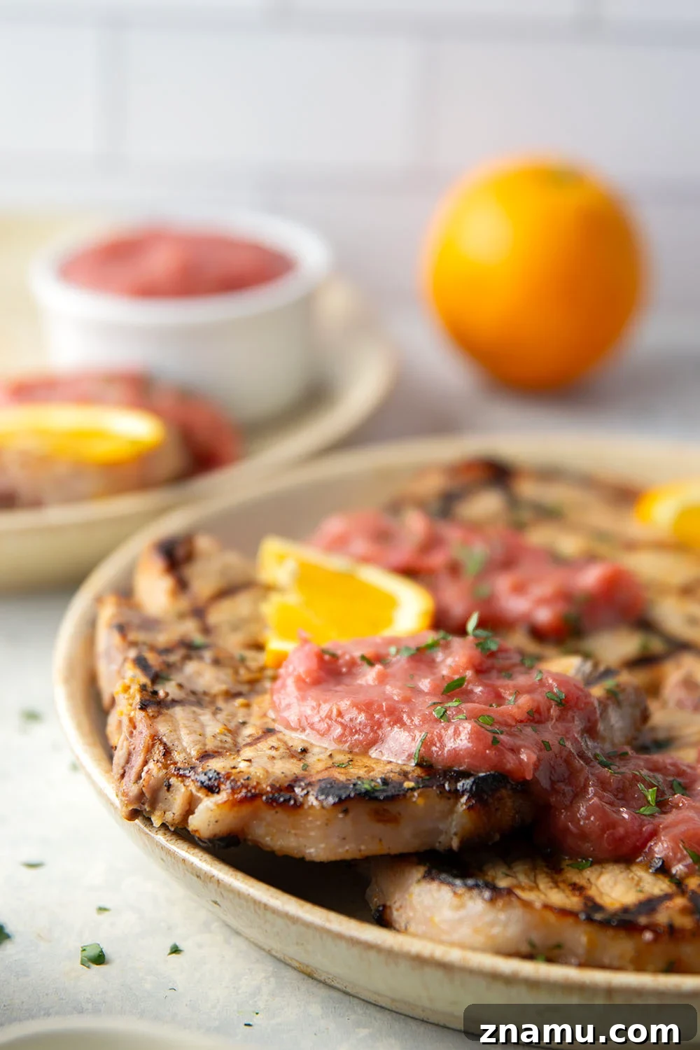These grilled orange pork chops feature pork chops marinated in a fresh orange marinade, grilled until perfectly juicy, and served with a sweet and tangy rhubarb compote.