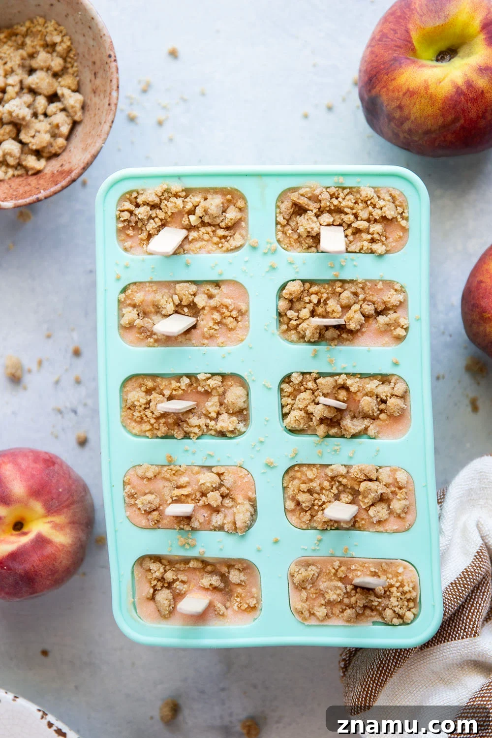 Juicy summer peaches and a crunchy brown sugar streusel are the perfect match in these multi-layered peach popsicles!