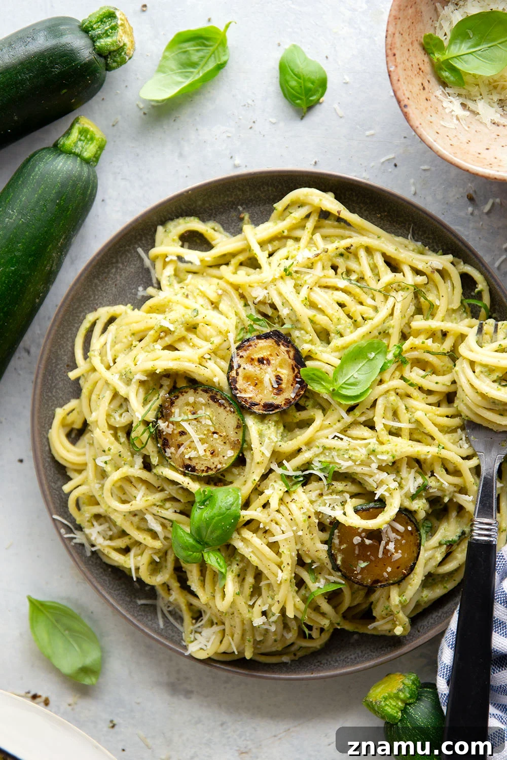 A bowl of creamy zucchini pasta garnished with basil and Parmesan.